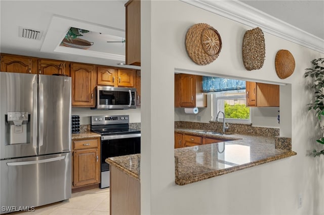 kitchen featuring stainless steel appliances, crown molding, sink, light tile patterned floors, and dark stone countertops