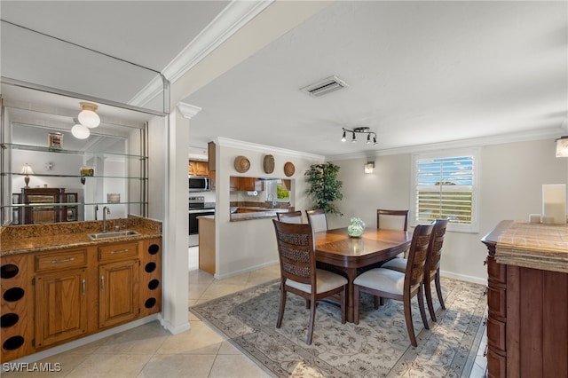 dining area with light tile patterned floors, crown molding, and sink