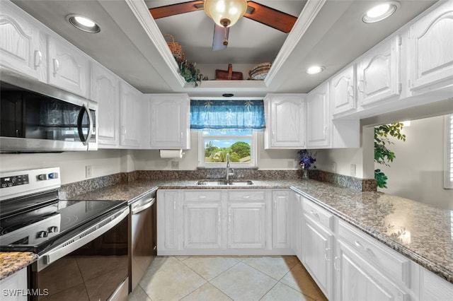 kitchen featuring appliances with stainless steel finishes, light tile patterned floors, white cabinetry, and sink