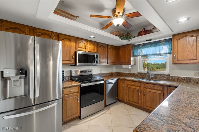 kitchen with sink, ceiling fan, light tile patterned floors, a tray ceiling, and stainless steel appliances