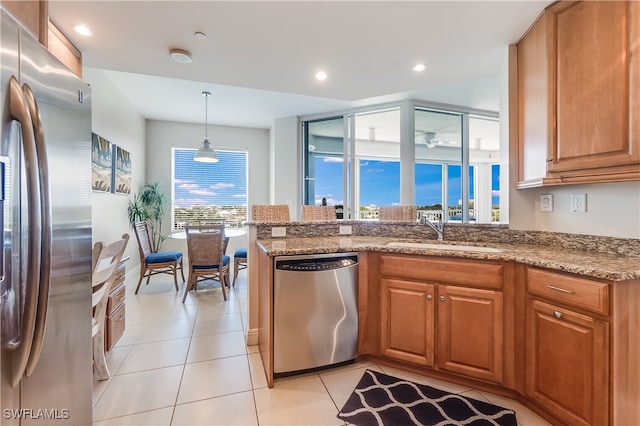 kitchen featuring light stone counters, light tile patterned flooring, stainless steel appliances, sink, and decorative light fixtures