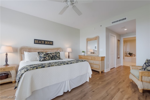 bedroom with ceiling fan, light wood-type flooring, and ensuite bath