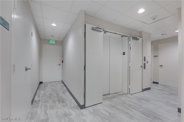 corridor featuring light hardwood / wood-style floors and a drop ceiling