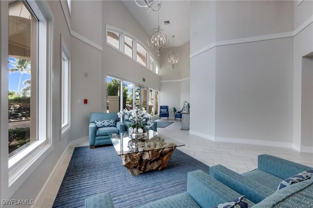 living room with a chandelier, high vaulted ceiling, and a wealth of natural light