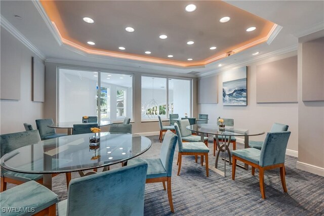 carpeted dining room with ornamental molding and a tray ceiling