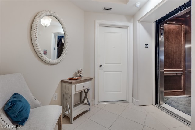 hallway featuring elevator and light tile patterned floors