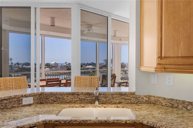 room details featuring sink, light brown cabinets, ceiling fan, and a water view