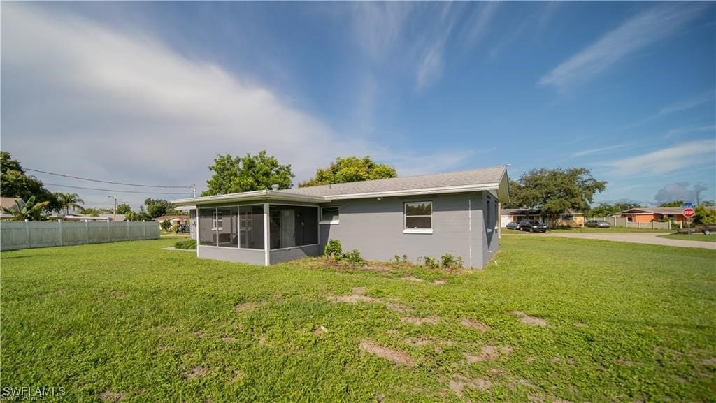 rear view of property featuring a sunroom and a lawn