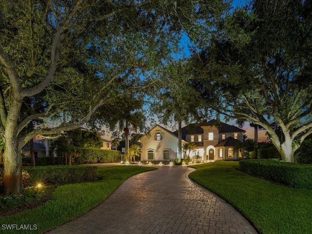 view of front of home with a front yard, decorative driveway, and stucco siding