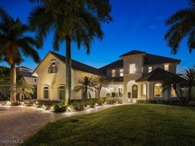 mediterranean / spanish house with stucco siding, a front lawn, and decorative driveway