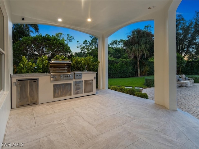 patio terrace at dusk featuring a yard, area for grilling, sink, and a grill