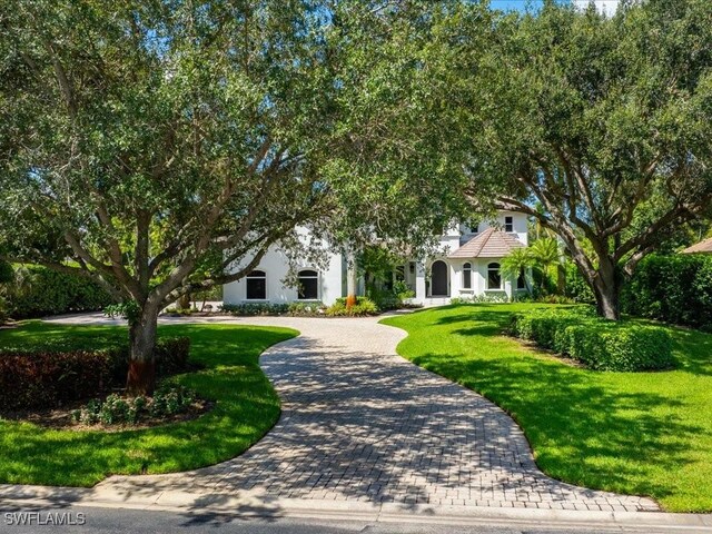 exterior space with a front yard, stucco siding, and curved driveway