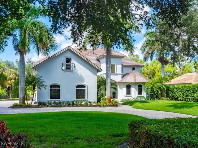 mediterranean / spanish-style home featuring a front lawn, a tile roof, and stucco siding