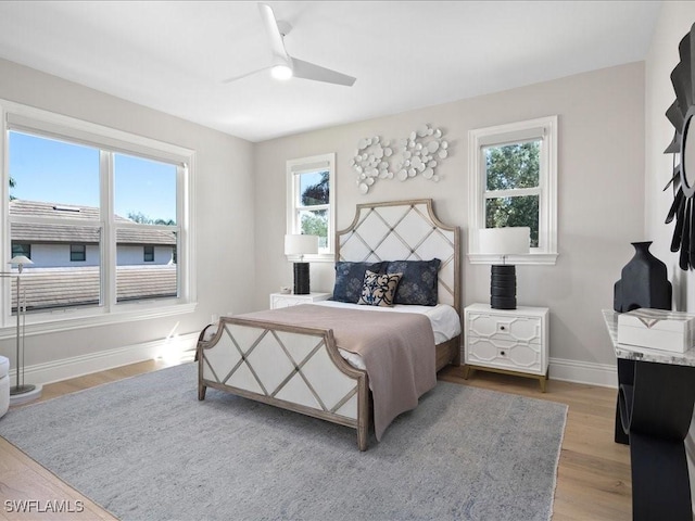 bedroom with light wood finished floors, baseboards, and a ceiling fan
