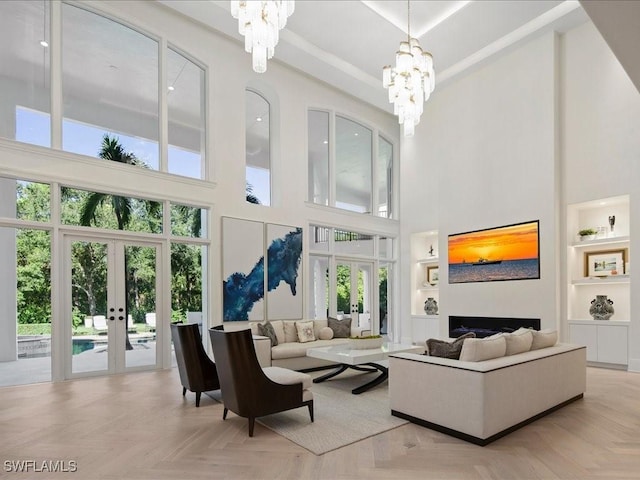 living room with built in features, french doors, and a chandelier