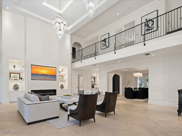 living room featuring a towering ceiling, a chandelier, light parquet flooring, and built in features