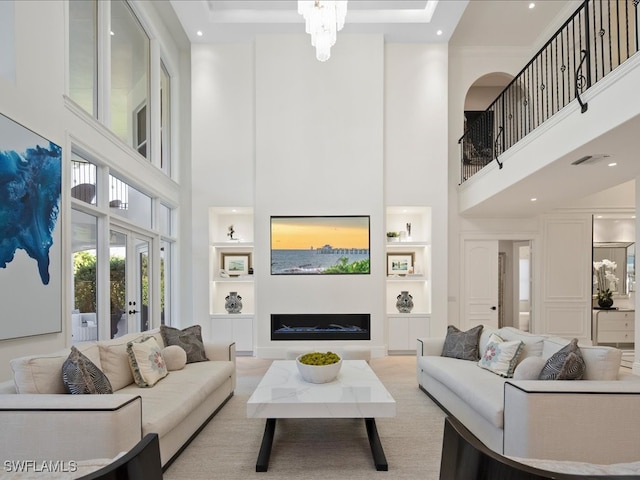 living room with french doors, a towering ceiling, and built in features