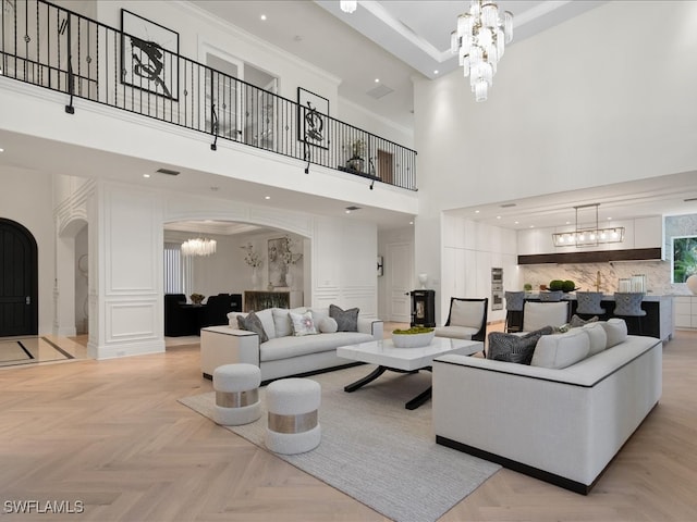 living room with light parquet floors, a high ceiling, and a chandelier