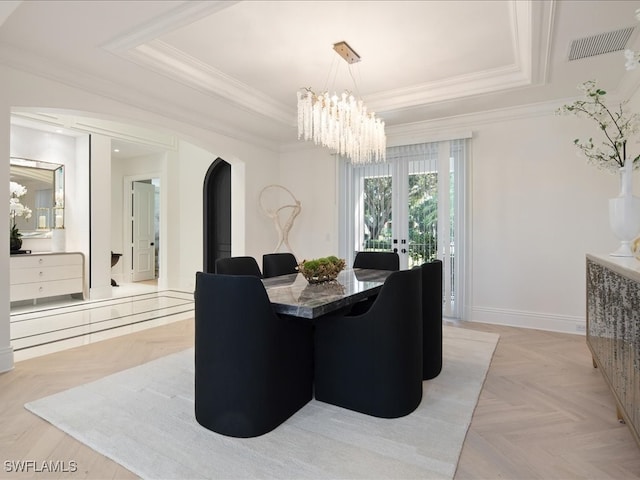 dining area featuring light parquet flooring, a raised ceiling, crown molding, an inviting chandelier, and french doors