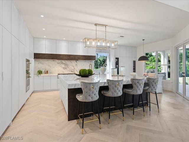 kitchen featuring white cabinetry, tasteful backsplash, a spacious island, hanging light fixtures, and modern cabinets