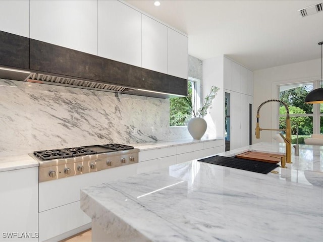 kitchen with stainless steel gas cooktop, a sink, light stone countertops, visible vents, and white cabinets
