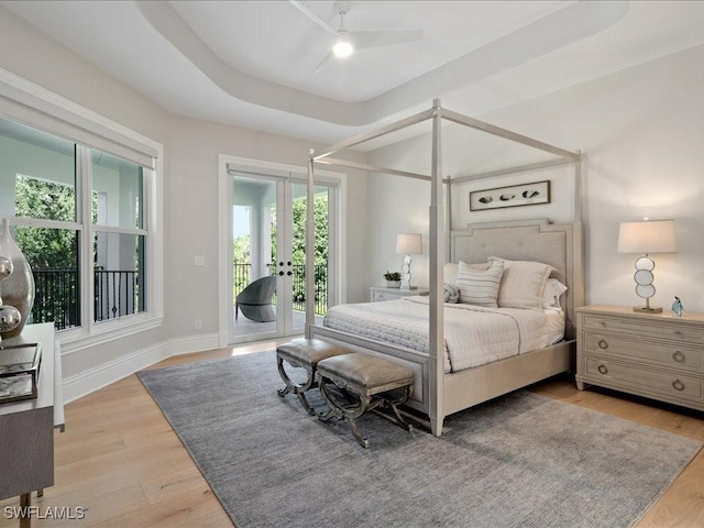 bedroom with french doors, a raised ceiling, wood finished floors, access to outside, and baseboards