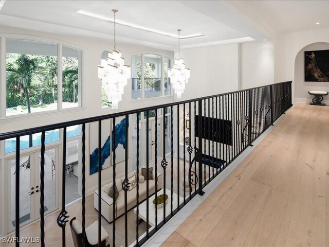 interior space featuring a notable chandelier, hardwood / wood-style floors, a raised ceiling, and a healthy amount of sunlight