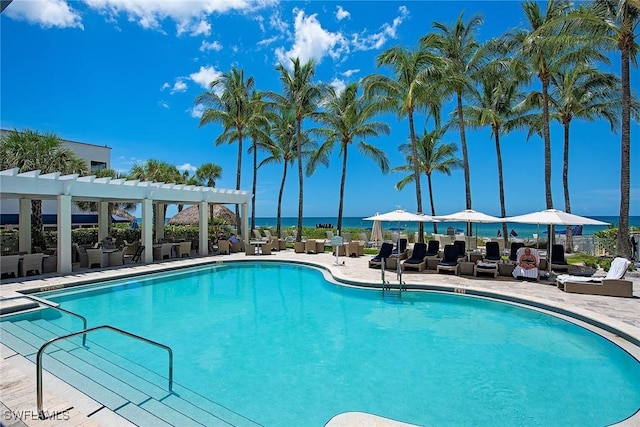 view of swimming pool with a patio area, a water view, and a pergola