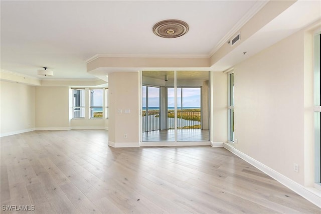 empty room with ornamental molding, a water view, and light wood-type flooring