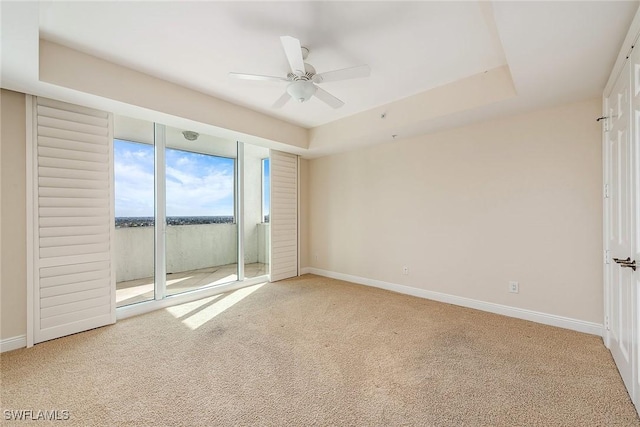 unfurnished room with carpet, ceiling fan, and a tray ceiling