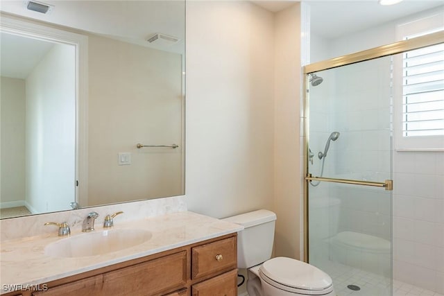 bathroom featuring toilet, vanity, and a shower with shower door