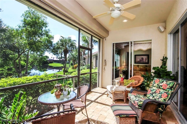 sunroom with a water view and ceiling fan