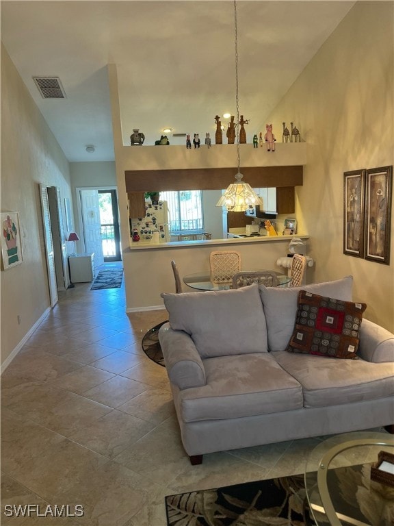 living room with tile patterned floors, vaulted ceiling, and a notable chandelier