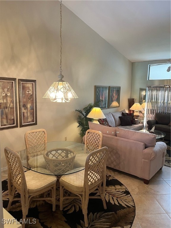 tiled dining area featuring ceiling fan with notable chandelier and high vaulted ceiling