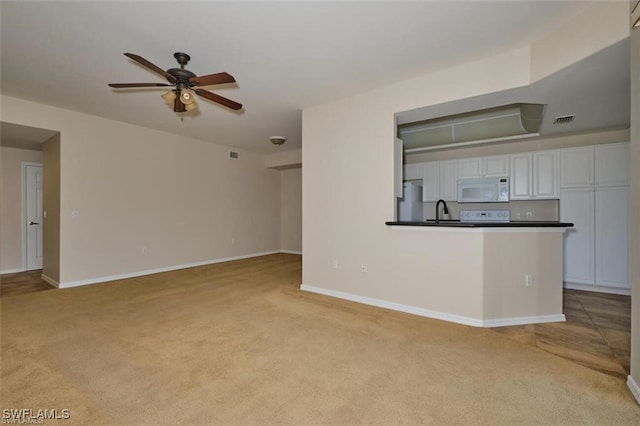 unfurnished living room with light carpet, ceiling fan, and sink