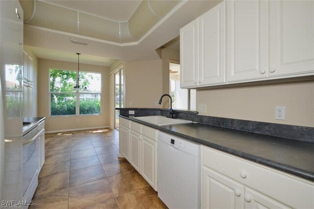 kitchen with white cabinets, pendant lighting, light tile patterned floors, sink, and white appliances