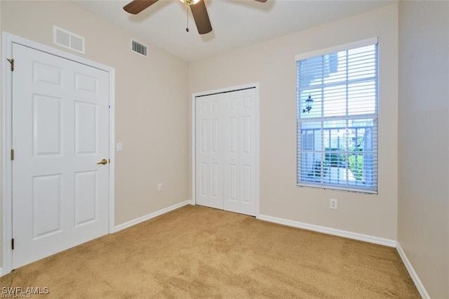 unfurnished bedroom with light carpet, a closet, and ceiling fan