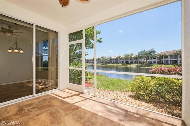 unfurnished sunroom featuring ceiling fan, plenty of natural light, and a water view