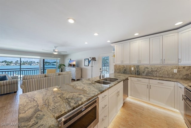 kitchen with light hardwood / wood-style floors, white cabinets, tasteful backsplash, and sink