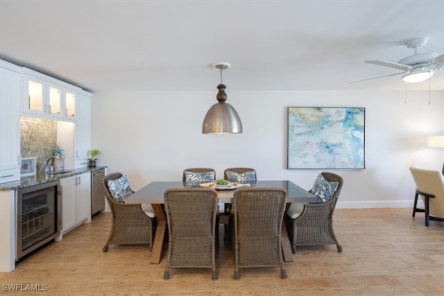 dining room featuring sink, ceiling fan, light hardwood / wood-style flooring, and beverage cooler