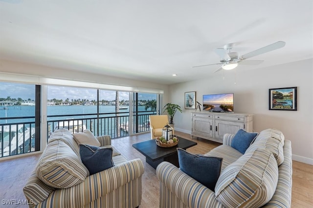 living room featuring light hardwood / wood-style floors, a water view, and ceiling fan