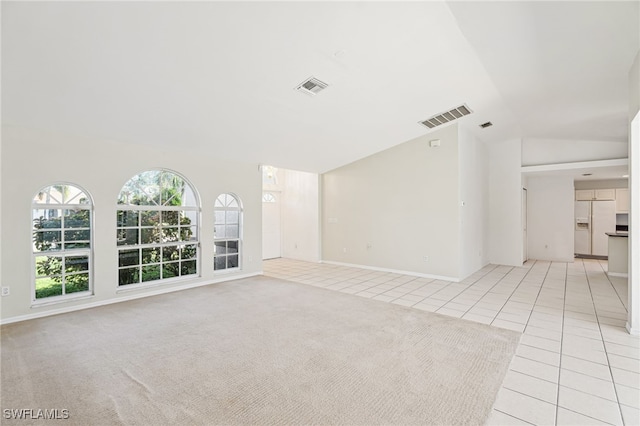 unfurnished living room featuring vaulted ceiling and light carpet