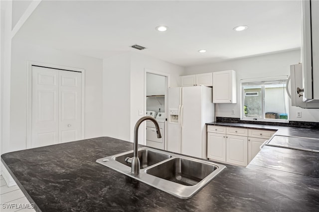 kitchen with white cabinetry, white refrigerator with ice dispenser, separate washer and dryer, and sink