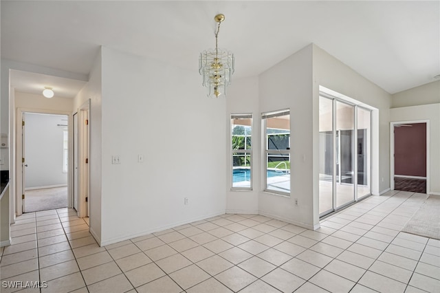 tiled spare room featuring vaulted ceiling and a chandelier