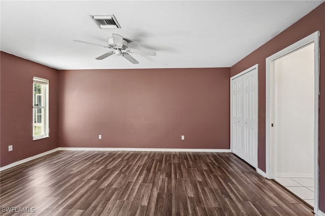 unfurnished bedroom with ceiling fan and dark wood-type flooring