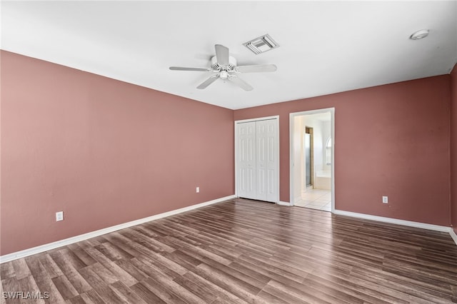 unfurnished bedroom with a closet, ensuite bath, ceiling fan, and hardwood / wood-style flooring