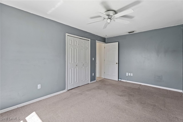 unfurnished bedroom featuring ceiling fan, light colored carpet, and a closet