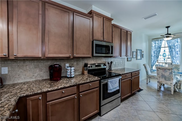 kitchen with tasteful backsplash, ceiling fan, appliances with stainless steel finishes, dark stone counters, and light tile patterned flooring