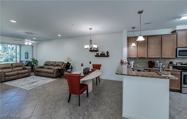 kitchen with dark stone countertops, stainless steel appliances, sink, and hanging light fixtures