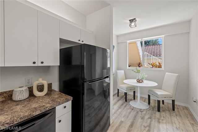 kitchen featuring black fridge, white cabinets, stainless steel dishwasher, dark stone counters, and light hardwood / wood-style floors